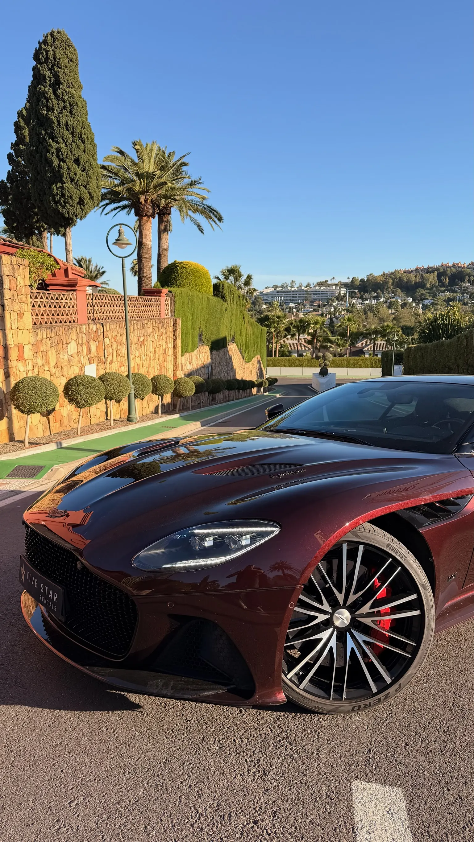 Aston Martin DBS Superleggera close-up front three-quarter view with clamshell bonnet, exposed carbon splitter and red Brembo carbon-ceramic calipers