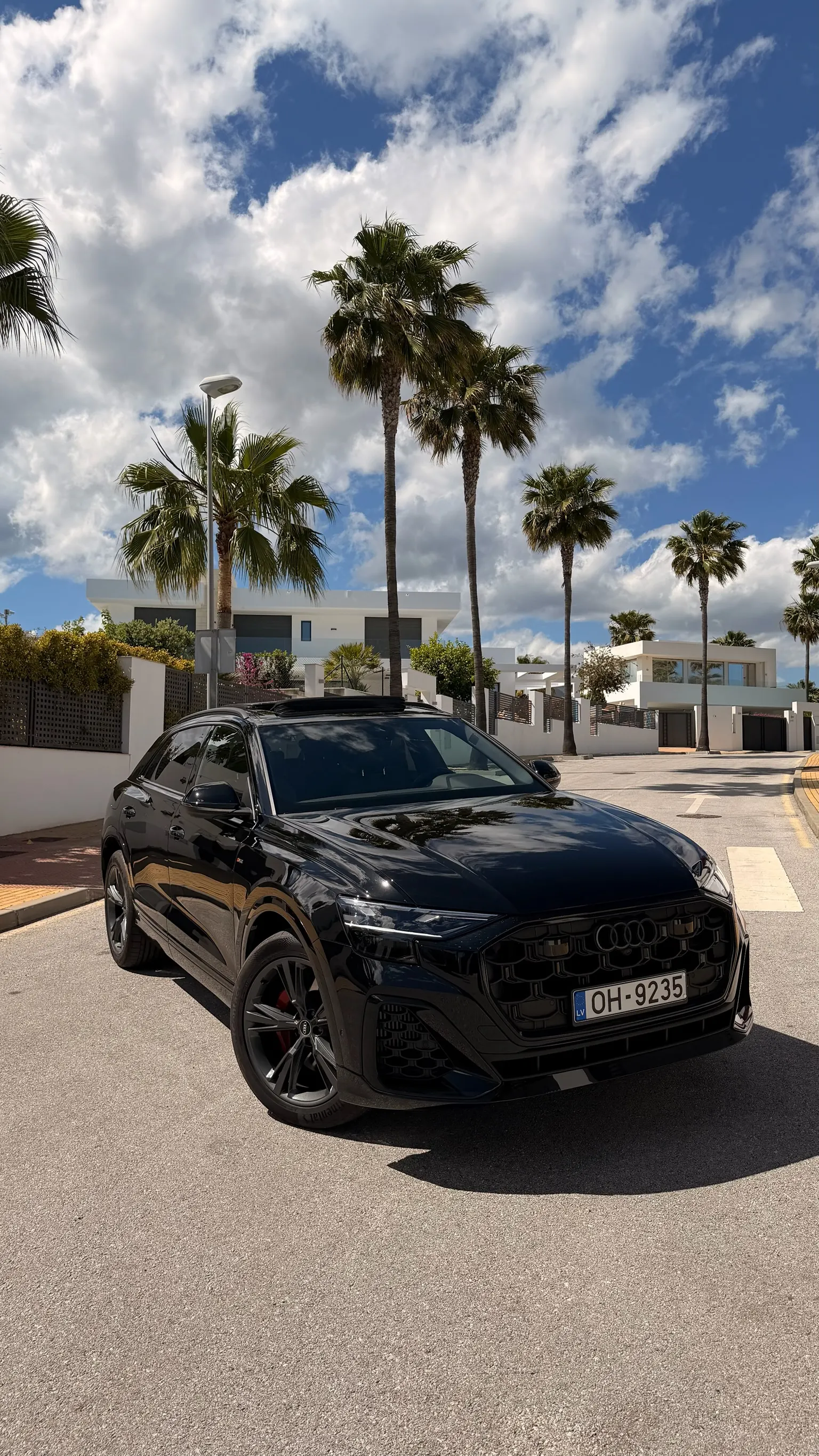Front view of the Orca Black metallic Audi Q8 55 TFSI with black Singleframe grille, HD Matrix LED headlights and S Line front bumper on a Marbella street