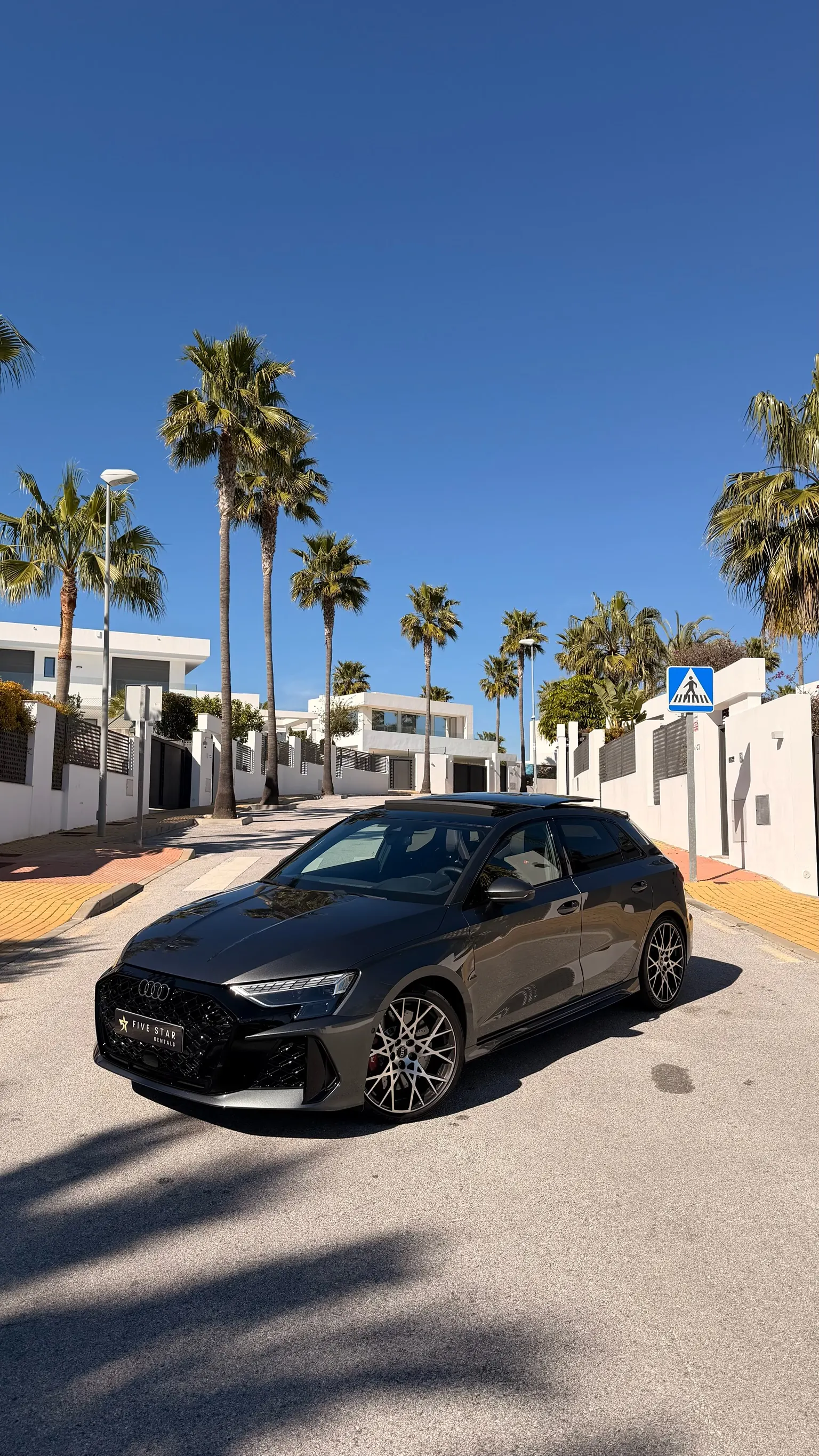 2025 Audi RS3 Sportback in Daytona Grey, front three-quarter view with Five Star Rentals plate and Marbella palm trees