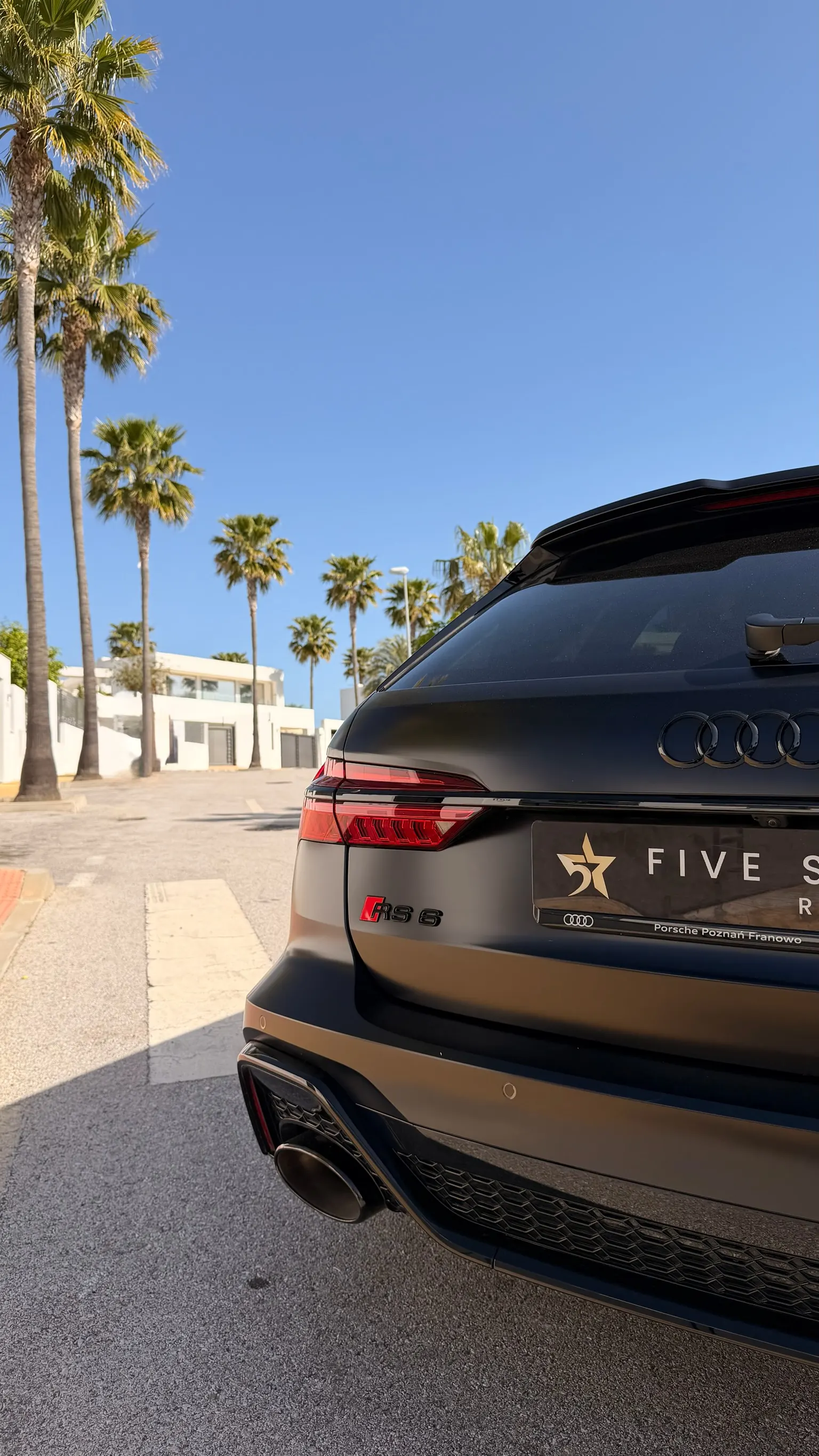 Audi RS6 rear detail with red RS 6 badge, black-chrome RS exhaust and Five Star Rentals plate