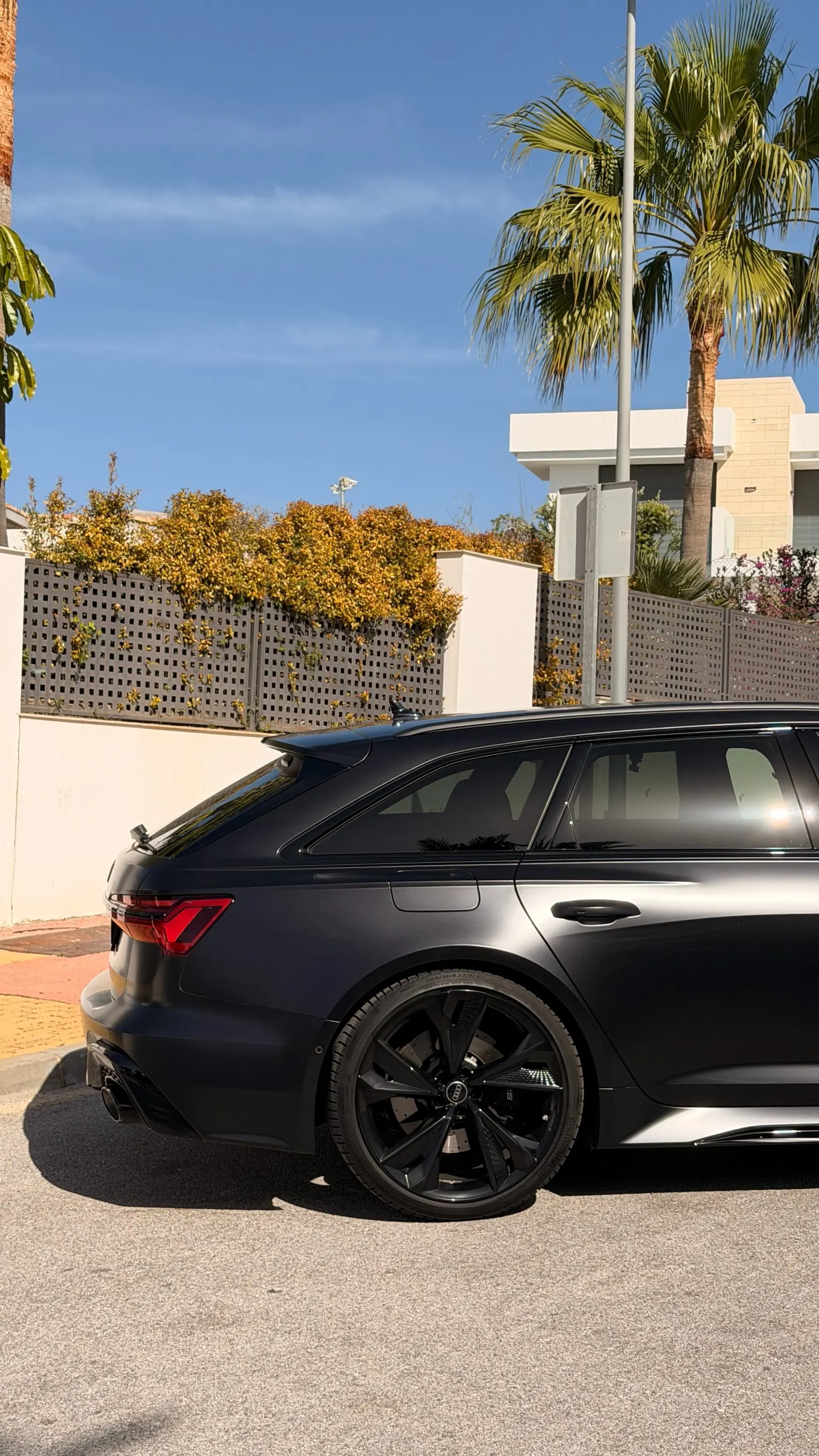 Rear side profile of the Mythos Black Audi RS6 Avant Performance with 22-inch 5-spoke dynamic wheel and black RS caliper