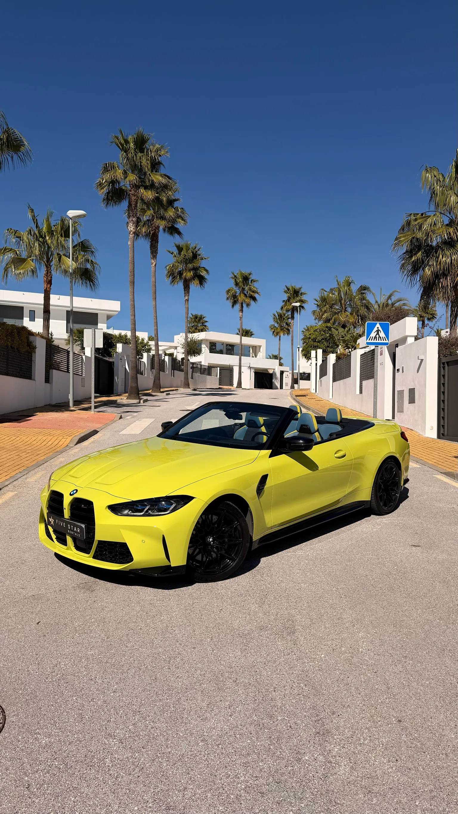 BMW M4 Competition Convertible in São Paulo Yellow with top down, front three-quarter view with Five Star Rentals plate on a Marbella street
