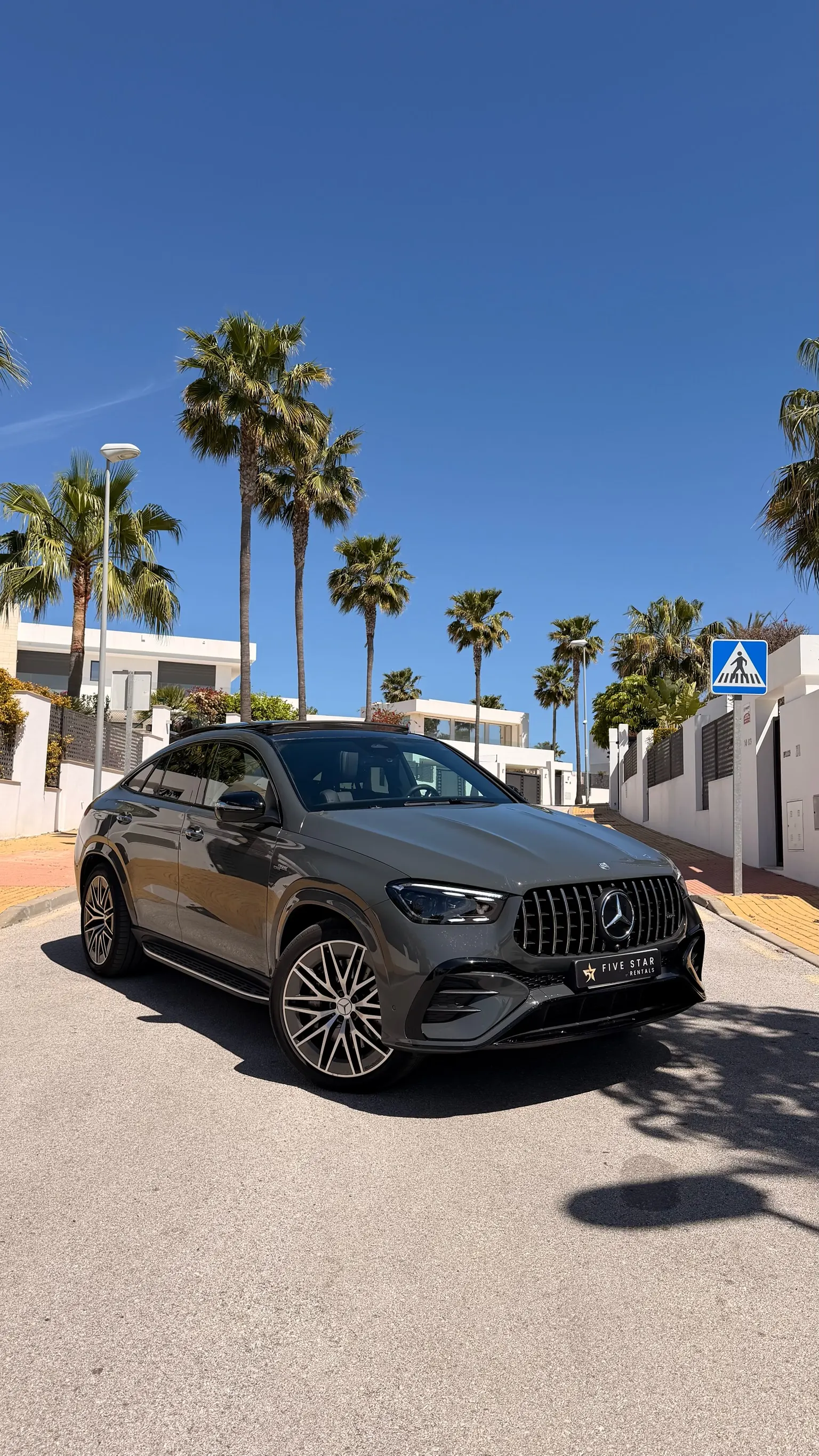 2025 Mercedes-AMG GLE 53 Coupé in Selenite Grey, front three-quarter view with Panamericana grille, Five Star Rentals plate and Marbella palm trees