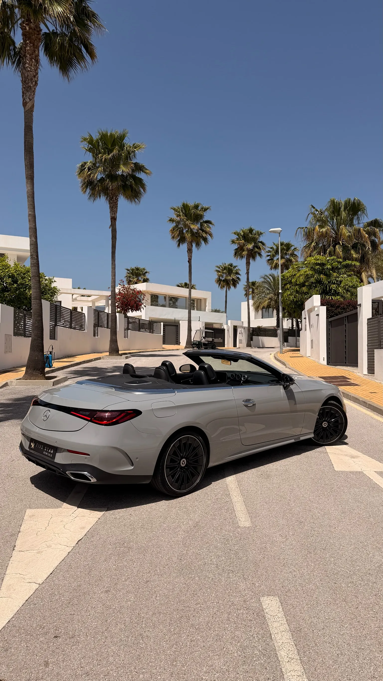 Rear three-quarter view of the Mercedes-Benz CLE 200 Cabriolet AMG Line with Five Star Rentals plate, dual exhaust and tonneau cover over the rear deck