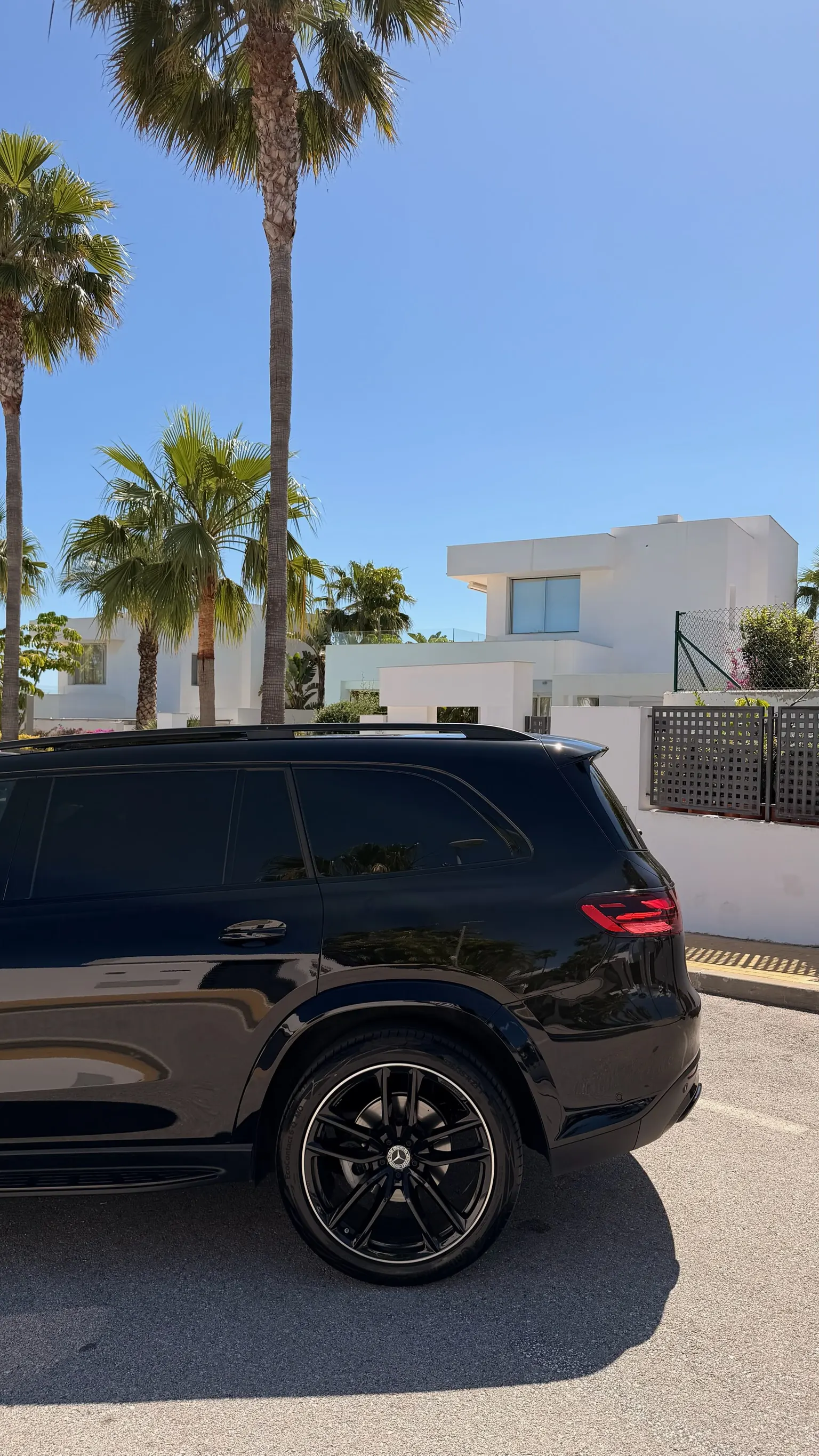 Mercedes-Benz GLS 580 4MATIC in Obsidian Black Metallic, front three-quarter view with Five Star Rentals plate, chrome grille and illuminated Mercedes star, Marbella palm trees