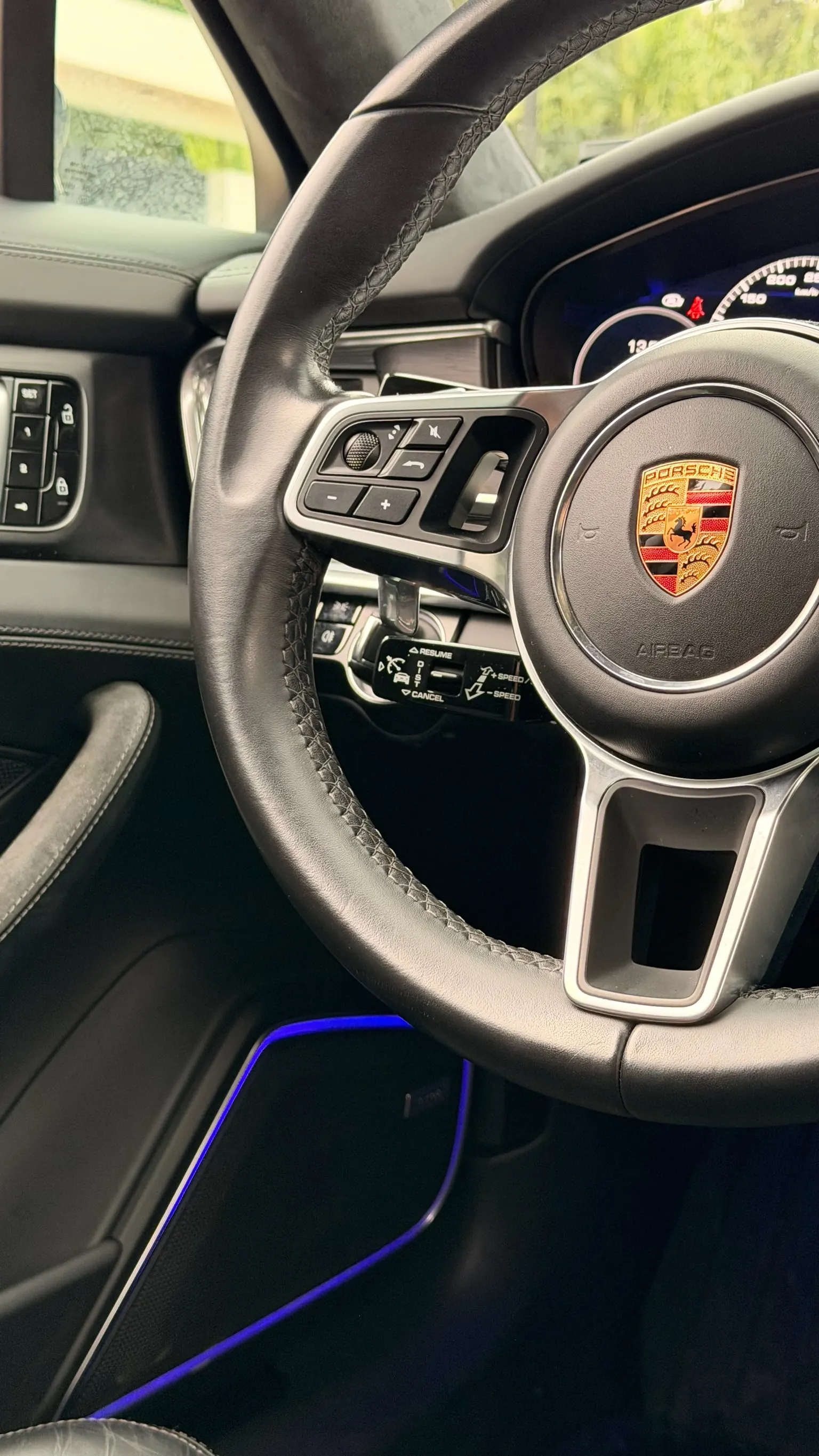 Close-up of Porsche GT sport steering wheel in leather with historic Stuttgart crest and multimedia controls