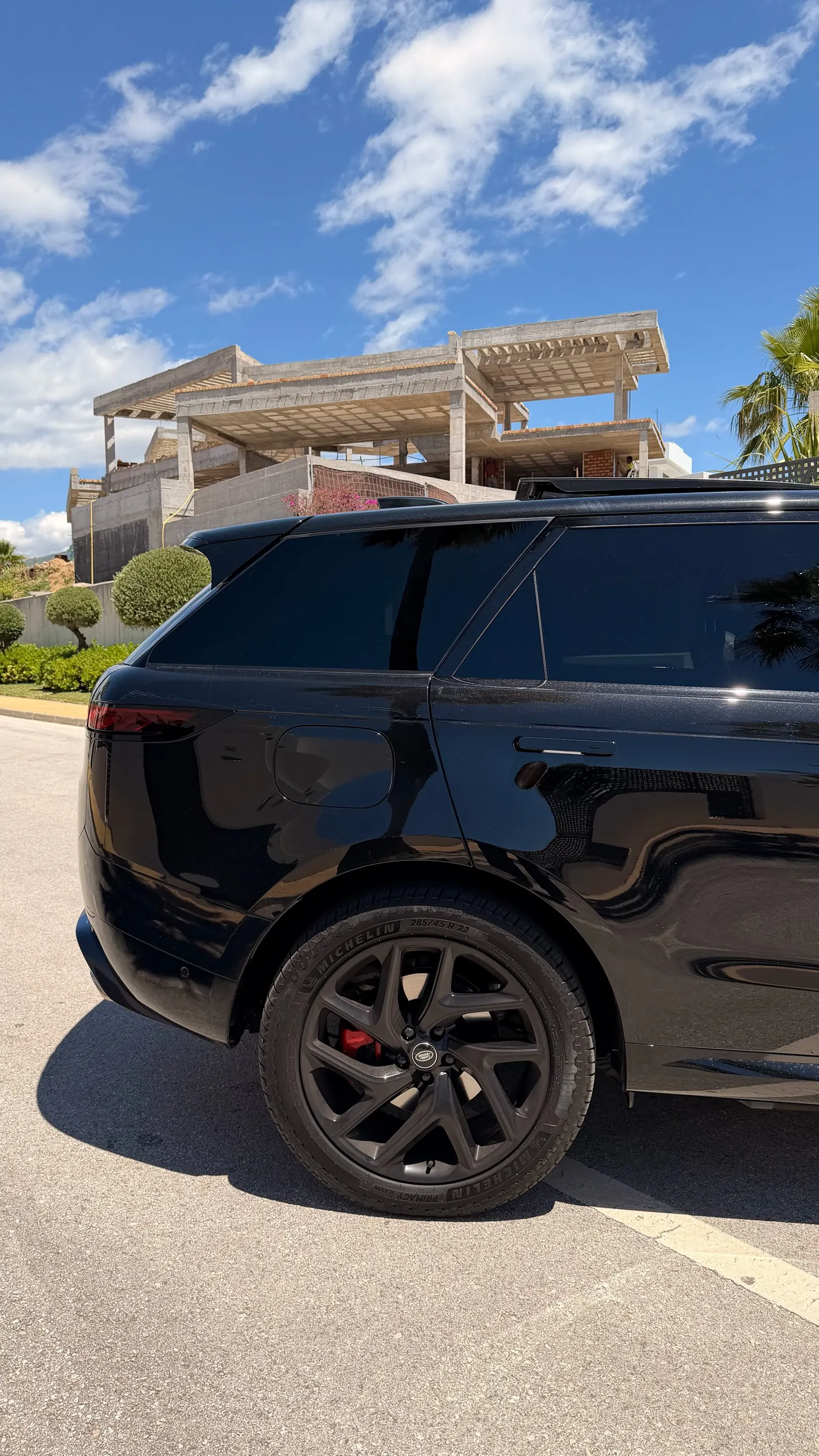 Rear three-quarter view of the Range Rover Sport P460e with integrated roof spoiler, electric charge port on the fender and 22-inch black wheel